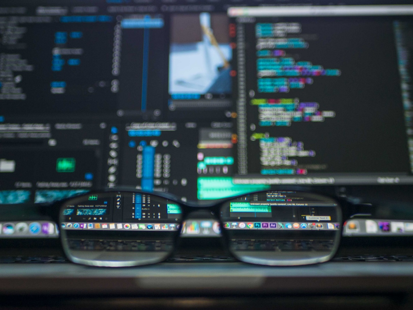 Eyeglasses sit on a laptop, bringing a screen showing various codes and stats into focus